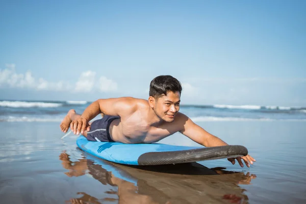 亚洲男子冲浪运动员在沙滩上的冲浪板上划桨 然后在海滩上训练 — 图库照片
