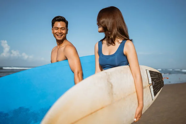 一对亚洲夫妇带着冲浪板在海滩边聊天 在蓝天下度假 — 图库照片