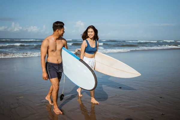 穿着泳衣的快乐夫妻带着冲浪板在沙滩上散步经过训练 健康的生活方式理念 — 图库照片