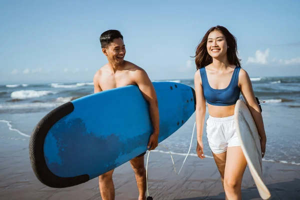 一对快乐的夫妇在海滩上抱着冲浪板 背景是蓝天 — 图库照片
