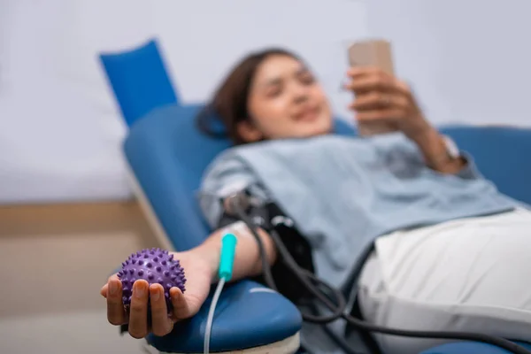 女性献血者在医院床上输血时手持硬物 — 图库照片