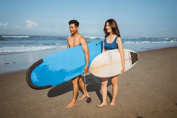 英俊的男子和美丽的亚洲女子与冲浪板沿着海滩散步 享受假期 — 图库照片