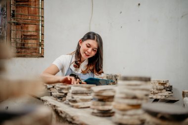 Taş atölyesinde taş yığınını tutan ve kontrol eden güzel bir kadın.