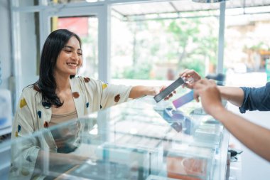 asian female customer smiling while choosing the vape mods helped by the male customer clipart