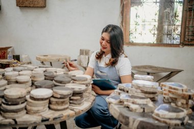 Asyalı kadın taş ustası işadamı bir depodaki taş yığınını kontrol ediyor.
