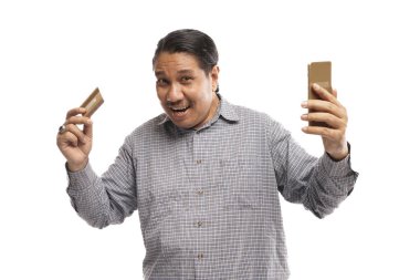 Yaşlı Asyalı adam elinde telefon ve kartla dikilip beyaz arka plandaki kameraya bakıyor.