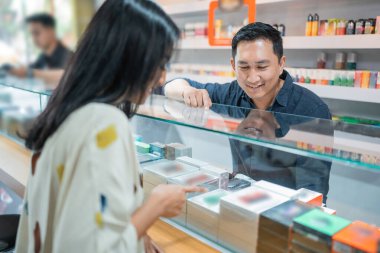 Kadın müşteri vitrin kutusunun içindeki vape modunu işaret ediyor