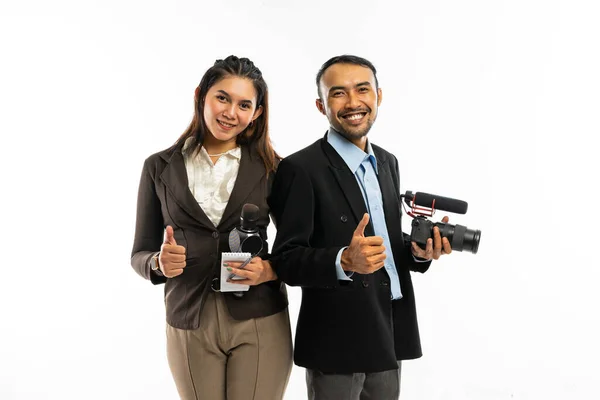 穿着棕色西装的女记者和身穿黑色西装的男记者站在一起 竖起大拇指笑着 — 图库照片