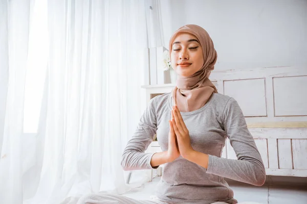健康なイスラム教徒の女性を身に着けているヒジャーブヨガのピラティス瞑想で部屋でオレンジマットレスの上に目を閉じてハスのポーズで部屋 — ストック写真