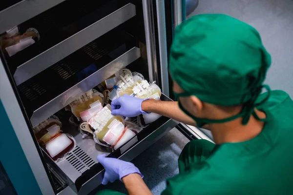 Orvos Egyenruhában Gumikesztyűvel Eltávolítja Vérzsákot Tárolószekrény Polcáról — Stock Fotó