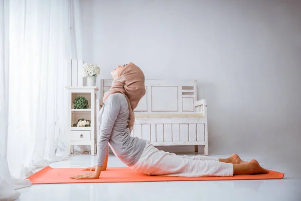 亚洲穆斯林女教官训练Bhujangsana眼镜蛇瑜伽时 要戴头巾在枕垫上 — 图库照片