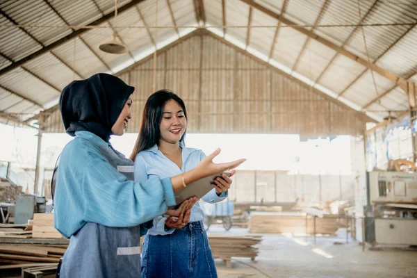 女性のイスラム教徒の起業家は タブレットで工芸品を選択し 直接木工ワークショップを見て女性の顧客にサービスを提供します — ストック写真