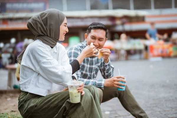 美しいイスラム教徒のカップルが道路脇に座りラマダーン中に路上販売店から購入した食べ物を楽しんでいます — ストック写真