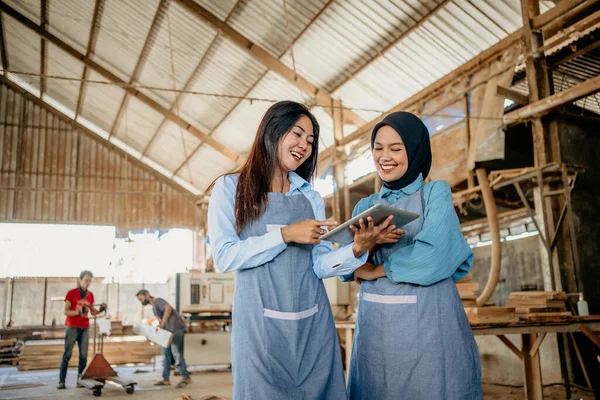 木工芸のワークショップでデジタルタブレットで彼女の友人と一緒に働くイスラム教徒の女性起業家 — ストック写真