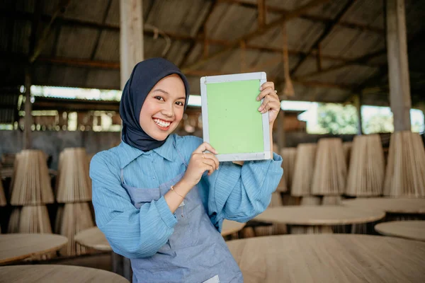 木製工芸品店のカメラに空白のタブレット画面を示すベールの女性起業家の笑顔 — ストック写真