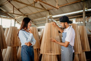 Asyalı erkek tezgahtar, bir ahşap dükkanında ahşap ürünleri seçerken müşterilere servis yapıyor.