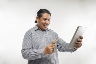 Elinde kredi kartı ve tabletle beyaz arka planda duran yaşlı Asyalı adam izole edilmiş.