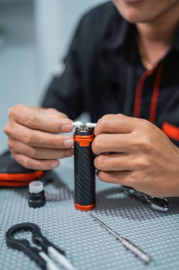 Erkek vape satıcısının portresi. Vape modundaki pamuk bobinlerini değiştiriyor.