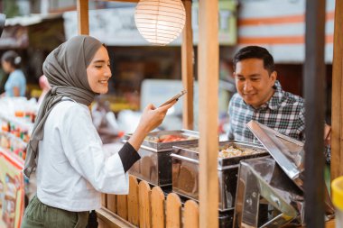 Adam yol kenarında el arabası olan çeşitli hamur köfteleri satıyor.