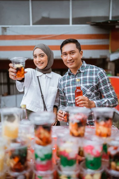 一个戴面纱的漂亮女孩和一个男人在街上卖混合果品饮料和果汁 — 图库照片