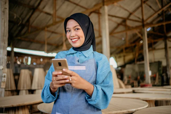 Asyalı Peçeli Kadını Bir Marangozhanede Dururken Akıllı Telefon Kullanıyor — Stok fotoğraf