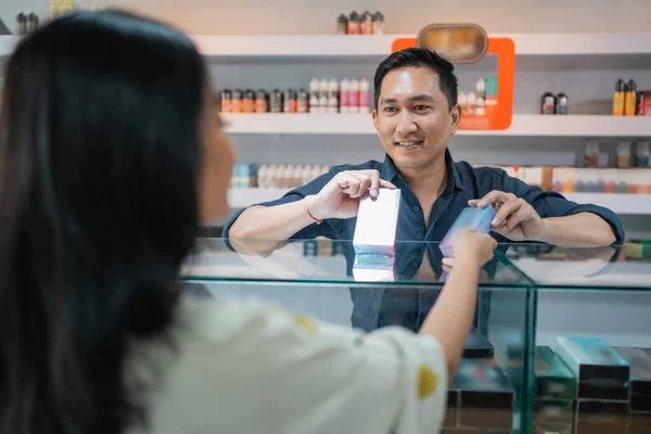 亚洲男性卖家向女性顾客提供蒸气模子的变体 — 图库照片