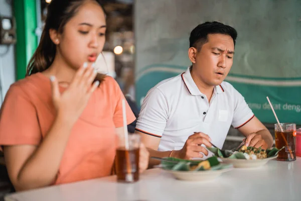英俊潇洒的男人 脸上带着辛辣的表情和亚洲女人一起在传统的食品店里吃山核桃 — 图库照片