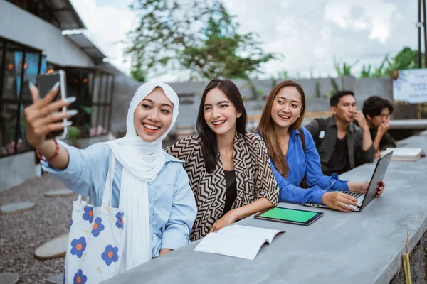 3人の女性アジア人学生が屋外のカフェに遊びながら携帯電話でセルフィーを撮る — ストック写真