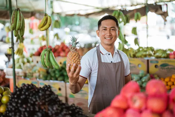 Męski Sprzedawca Fartuchu Trzymający Ananasa Sklepie Owocowym — Zdjęcie stockowe