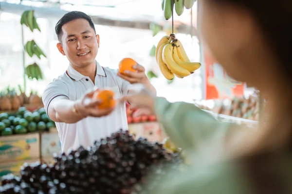 Mandarin Meyvesini Meyve Dükkanındaki Diğer Müşteriye Verirken Gülümseyen Erkek Müşteri — Stok fotoğraf