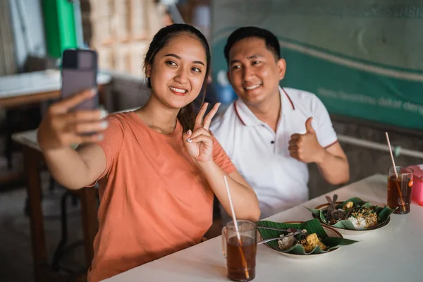 デートの女と男は伝統的な屋台で一緒に食事をしながら自撮り — ストック写真