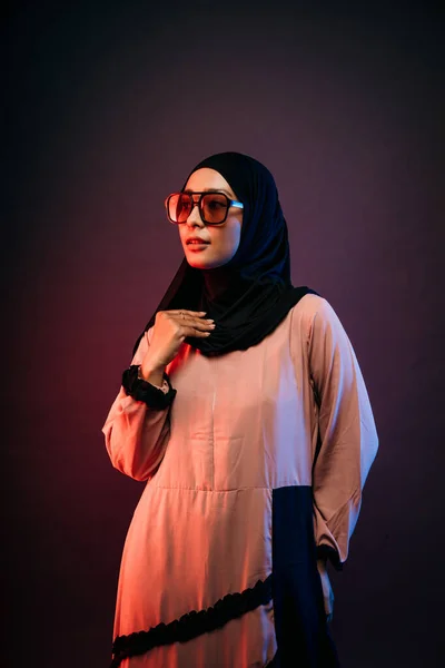 穆斯林妇女身穿黑色头巾橙色长裙 戴着太阳镜 左手插在口袋里向侧面看 — 图库照片