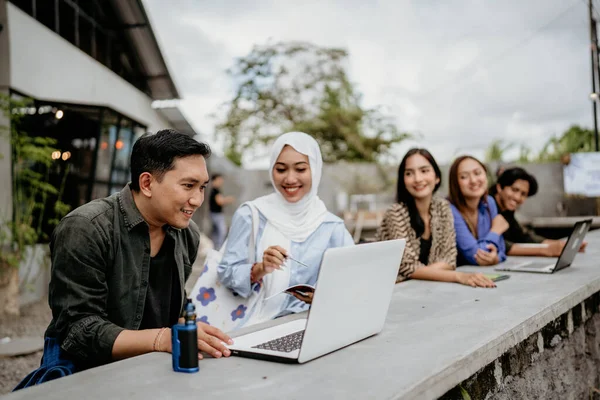 屋外のコワーキングスペースでラップトップコンピュータを使用しているアジアの男性と女性の大学生 — ストック写真