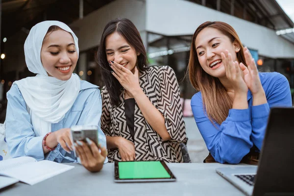 3人のアジア系女子学生が屋外のカフェで携帯電話 タブレット ノートパソコンを使って座っています — ストック写真