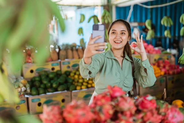 女顾客站在水果店用手机拍照时 举手表决 — 图库照片
