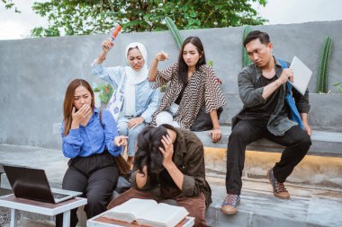 Bazı öğrenciler erkek gruptaki arkadaşlarına kampüsün dışında birlikte otururken zorbalık yapıyorlar.