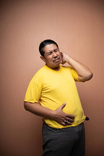 肥胖的亚洲老人的特征 腹部伸展的肥胖老人在与外界隔绝的普通背景下触摸着自己的胃 感到不快乐 — 图库照片