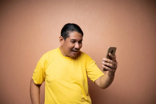 Sarı Tişört Giyen Yaşlı Asyalı Bir Adam Cep Telefonu Tutuyor — Stok fotoğraf