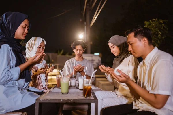 屋外のカフェで断食をする前に一緒に祈る若いアジア人のグループ — ストック写真