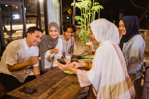 屋外のカフェで断食をしながら携帯電話を見ているイスラム教徒の友人のグループの肖像画 — ストック写真