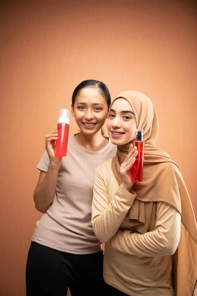 Две Женщины Хиджабом Хиджаба Кремовой Футболке Улыбаясь Держа Бутылку Кожи — стоковое фото