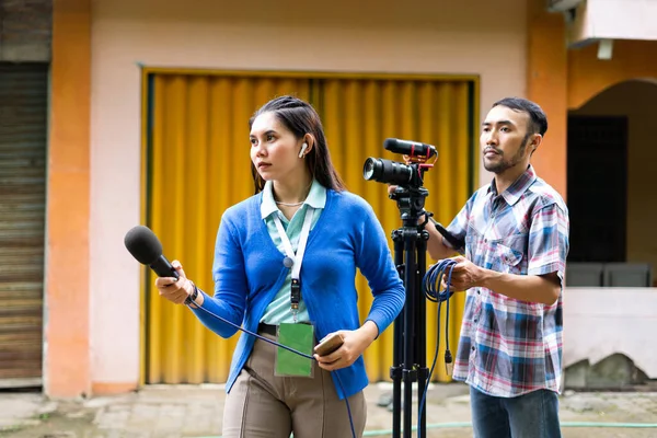 Mavi Hırkalı Bir Kadın Muhabir Arkasında Bir Kameraman Yeşil Isim — Stok fotoğraf