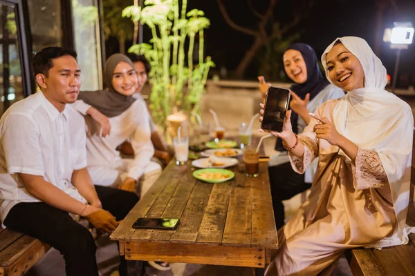 イスラム教徒の女性と友人は屋外カフェで一緒に断食をしながら画面電話を表示します — ストック写真