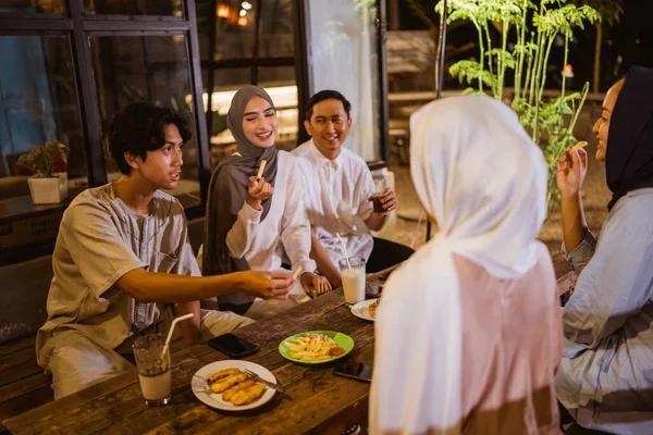 イスラム教徒の女性と男性のグループは屋外のレストランで一緒に断食をしながら軽食や飲み物を食べます — ストック写真