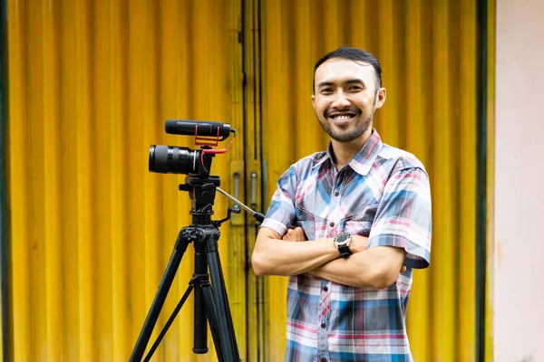 一个穿着格子呢衬衫的摄影师站在他的拍摄器材旁边 面带微笑地站着 — 图库照片