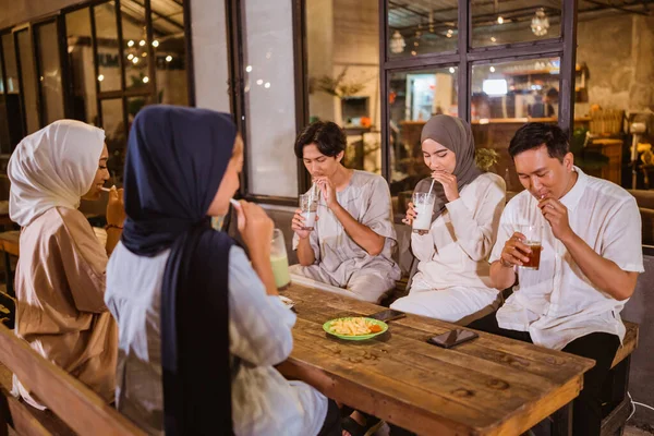 一群蒙面的穆斯林妇女和穆斯林男子在聚餐期间用杯子里的稻草喝水 — 图库照片