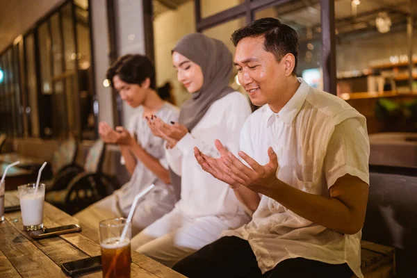三个年轻人一边吃饭一边在户外咖啡馆吃饭 一边祈祷 — 图库照片