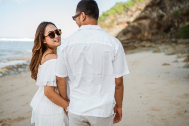 Beyaz elbiseli şirin genç bir çift sahilde birlikte geziyorlar.