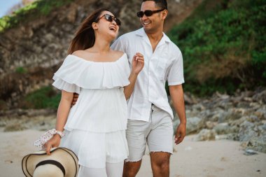 Mutluluk ve gülümseme, bir adamla bir kadının kumsalda birlikte yürümesi.