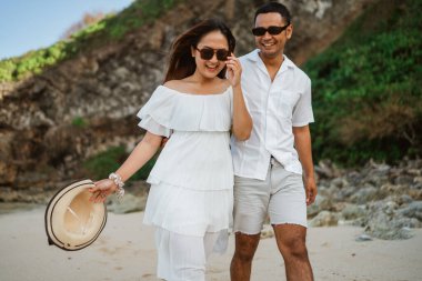 Beyaz elbiseli şirin genç bir çift sahilde birlikte geziyorlar.